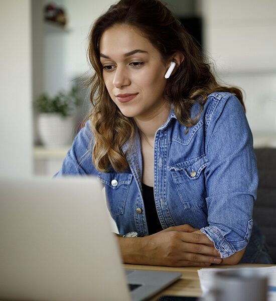 Young woman with bluetooth headphones having video conference at home